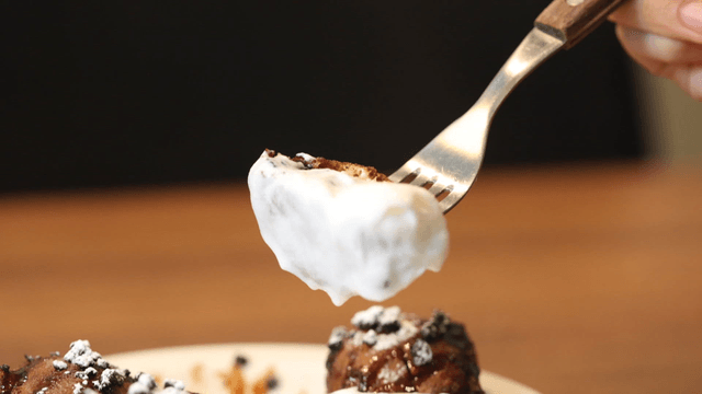 Chocolate dessert dipped in whipped cream with fork