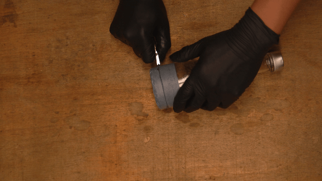 Craftsman cutting a glass bottle with masking tape on workbench