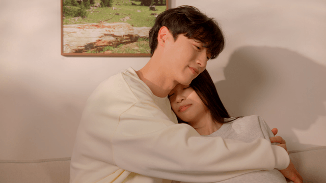 Pregnant newlywed couple embracing on sofa