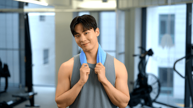 Young man smiling with a towel around his neck in a gym