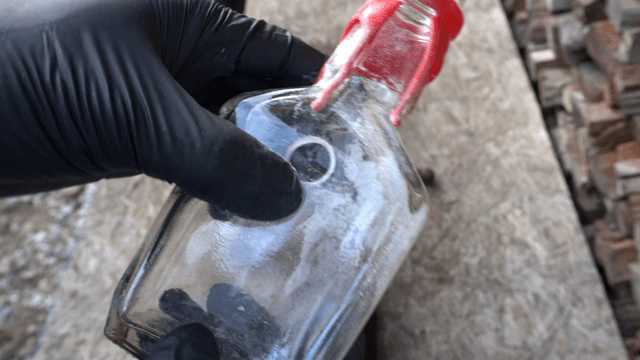 Gloved hand holding a glass bottle