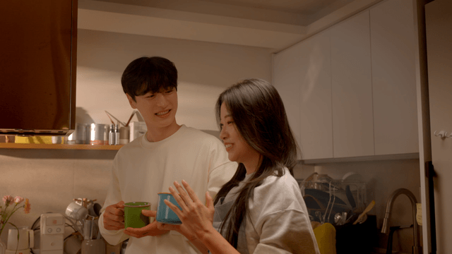 Couple talking in kitchen with warm drink