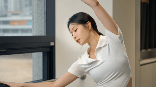 Young woman stretching by the window