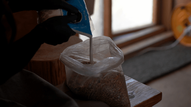 Woodcraft artisan pouring wood glue into plastic sawdust bag