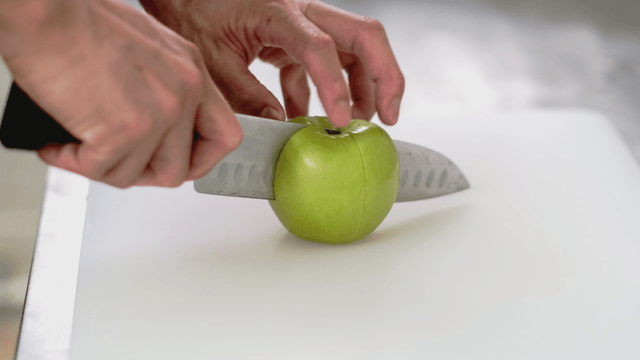 Slicing a green apple on a cutting board