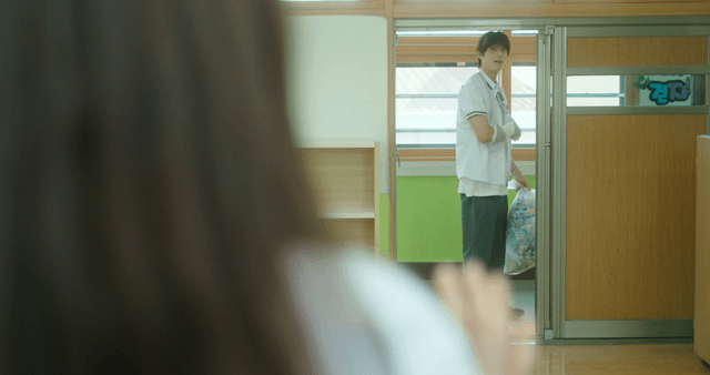 Student carrying trash in a classroom