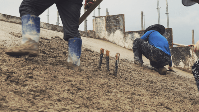 Workers smoothing wet concrete on a slope