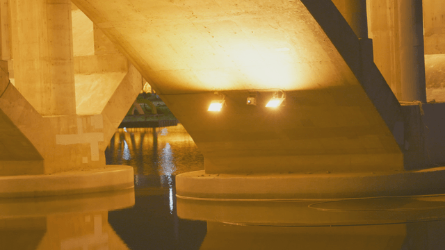 Night river under illuminated bridge structure