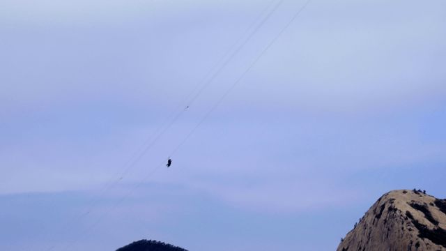 산악 지형 위로 집라인을 타는 사람