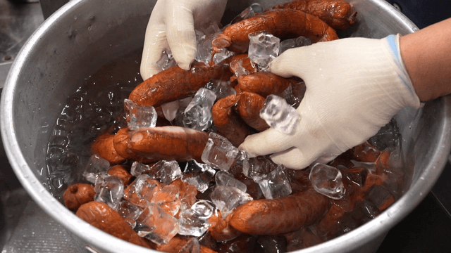 Chef cooling sausages in ice water
