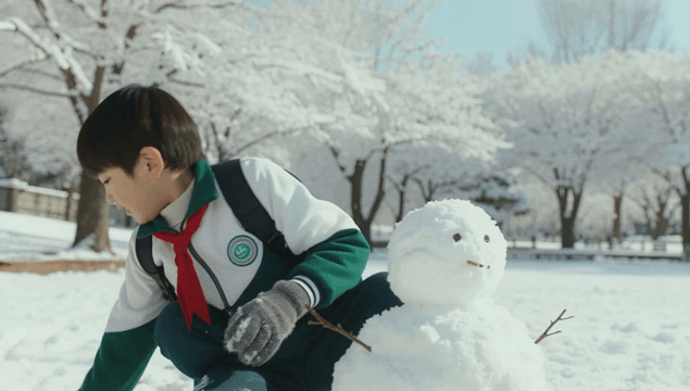 Boy building a snowman in a snow-covered park