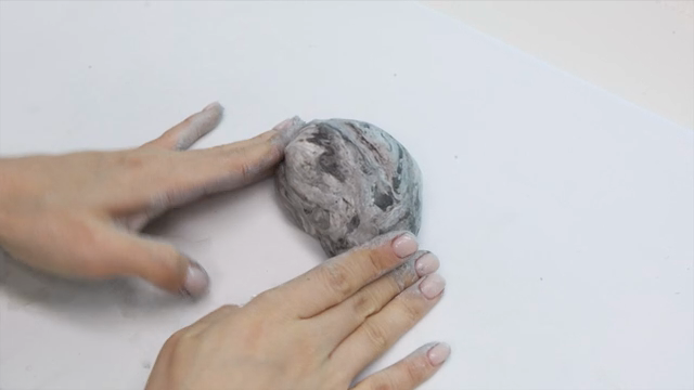 Hands shaping clay on a white surface
