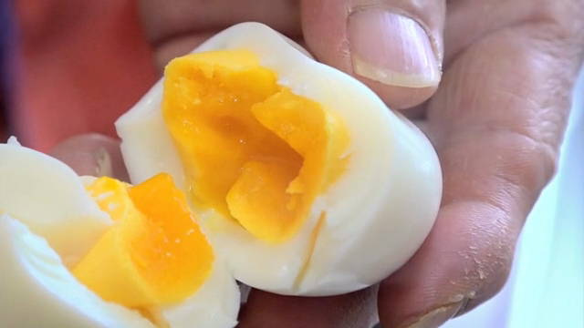 A hand holding a soft-boiled egg