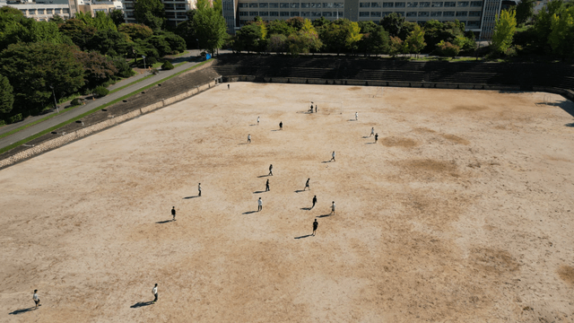 Students playing soccer on a dirt field