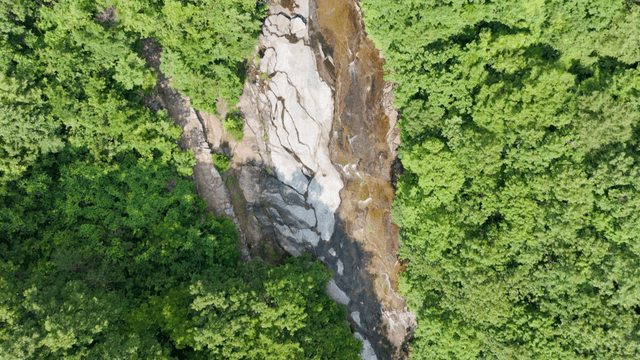 Aerial view of valley on massive rock revealed between forests