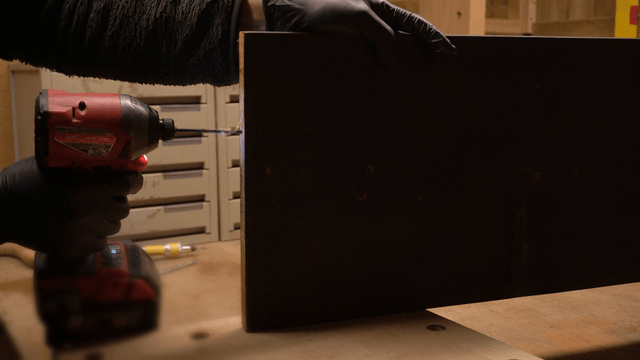 Electric drilling work on wooden board in workshop