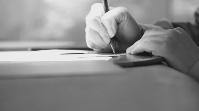 Hands writing on paper on table