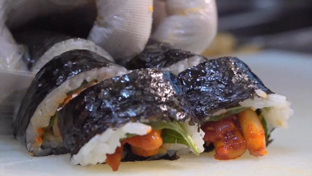 Gimbap being sliced on a cutting board