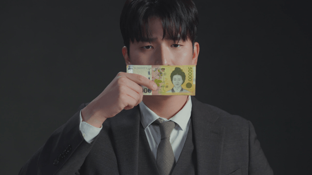 Man with a frustrated expression covering his mouth with money