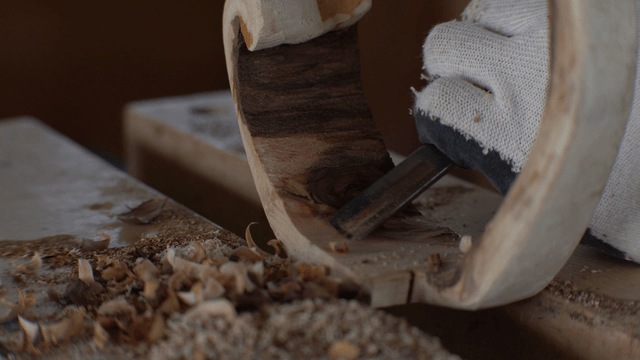 Hands carving wood with a fine chisel