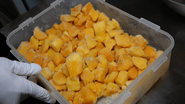 Frozen mango pieces in plastic container