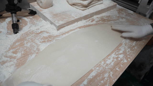 기계로 뽑은 반죽을 테이블 위에 올려놓는 장면