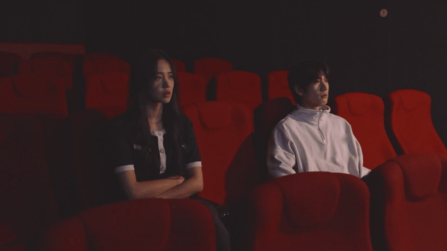 Couple sitting separately and watching a movie in a movie theater