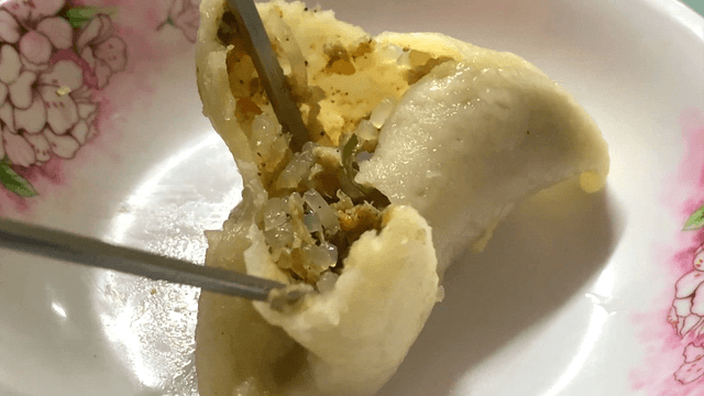 Chopsticks taking out the filling of a dumpling in a bowl