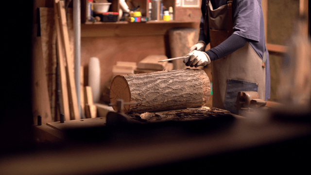 Craftsman working on a log in a workshop