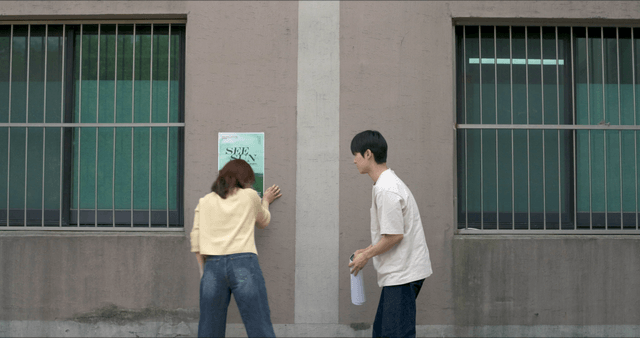 Two people posting poster on wall