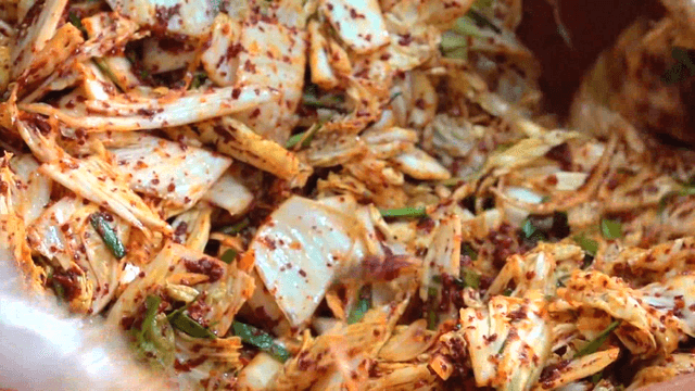 Red fresh kimchi being mixed in a large basin