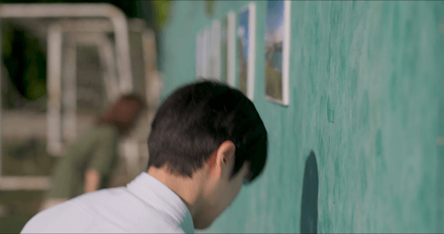Man arranging photos on a green wall