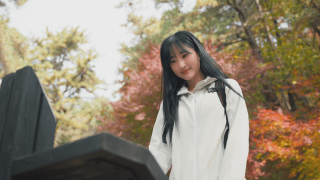 Young woman checking mountain sign in autumn forest