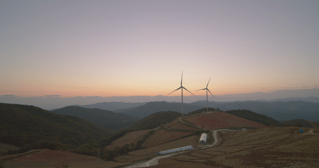 일출에 언덕 위의 풍력 터빈