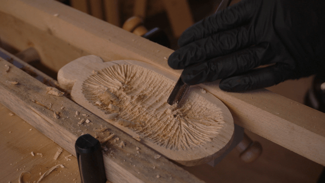 Hands of artisan carving wood with chisel in workshop