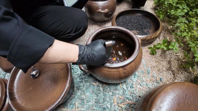 A spoon scooping soy sauce from a pot