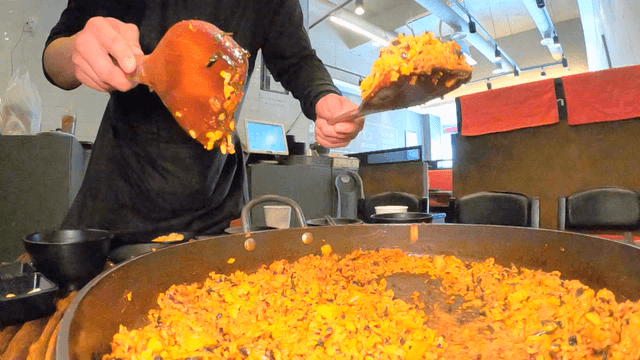 Spatula scooping fried rice from iron plate