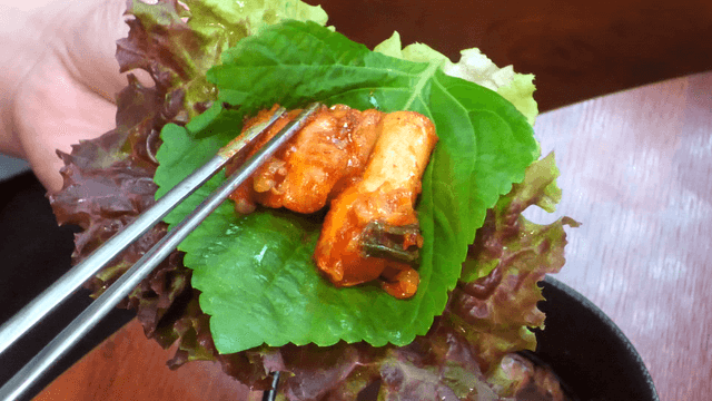 Spicy stir-fried chicken wrap with lettuce and perilla leaves