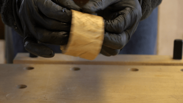 Gloved hand applying finishing oil to wood piece