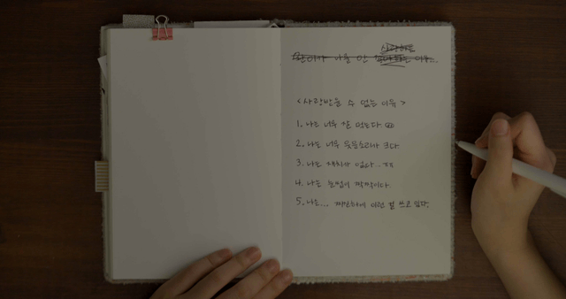 책상 위에서 일기를 쓰는 사람