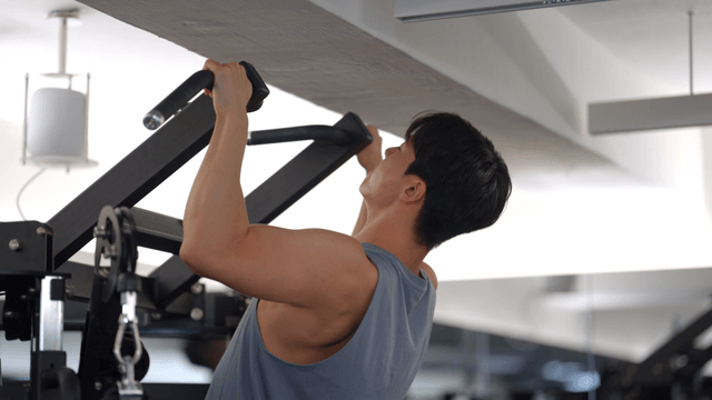 Young man training on pull-up machine
