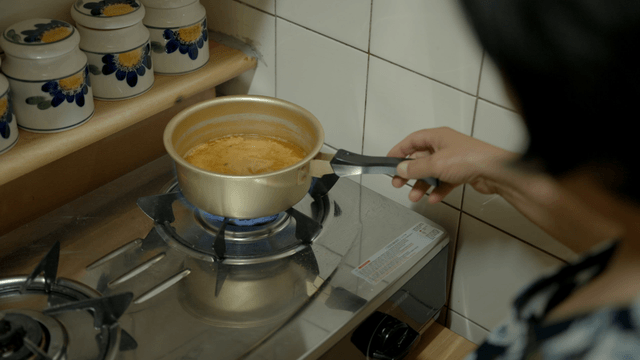 A person cooking ramen on a gas stove