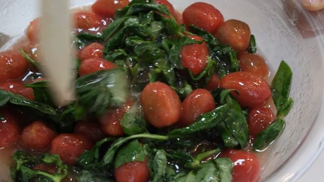 Mixing fresh tomatoes and greens in a bowl