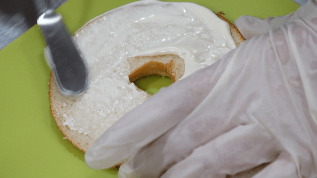 Spreading cream cheese on a bagel