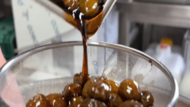 Green plum extract being strained through a sieve