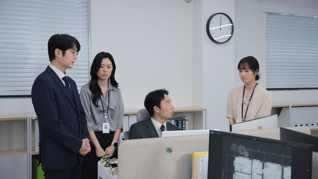 Office workers gathered around a desk, being scolded