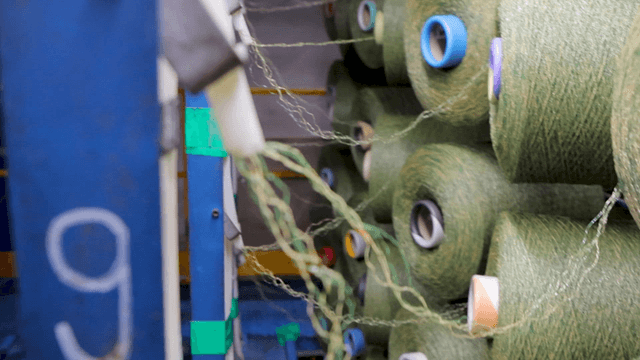 Green yarn spools stacked in a factory
