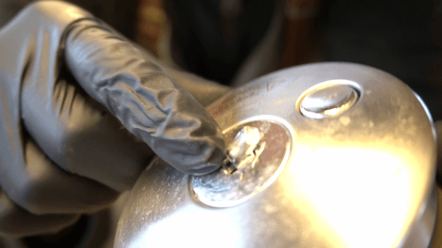 Gloved hand inspecting a metal part