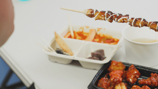 Person eating teriyaki chicken skewers