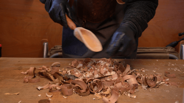 Wooden scoop clearing wood chips on workbench